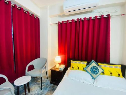 ダッカにあるEntire place- Ac 2BHK Apartment Basundhara R/Aの赤いカーテン、ベッド1台、テーブルが備わるベッドルーム1室が備わります。