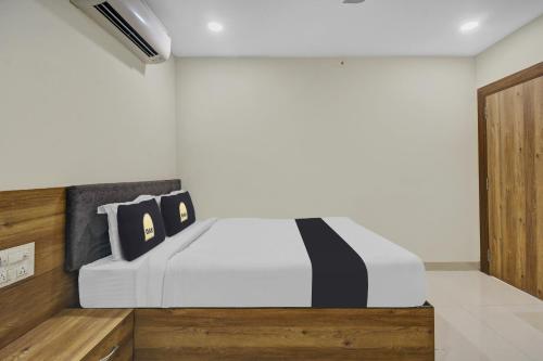 Collection O Hotel Swagath Pride في Mancherāl: غرفة نوم بسرير ابيض مع مخدات سوداء