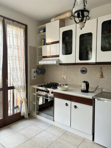 uma cozinha com armários brancos e um fogão em A Casa San Pietro - bilocale centro storico - Cyclist-friendly em Castel San Pietro Terme