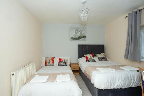 two twin beds in a bedroom with a chandelier at Saffron Studios in Orpington