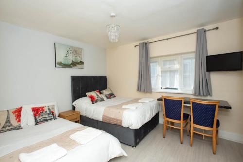a bedroom with two beds and a table and chairs at Saffron Studios in Orpington
