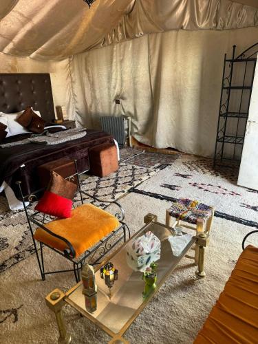 a room with a bed and a table and a chair at Sahara Desert Camp in Hassilabied