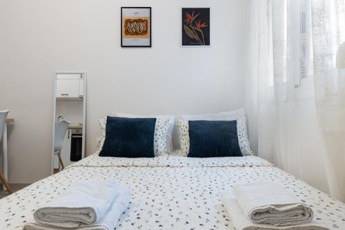 a white bedroom with a bed with blue pillows at Micro Studio 10 in Xanthi