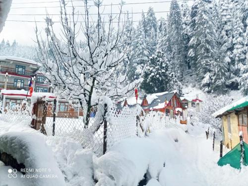a village covered in snow with a fence and trees at Secrets of Parvati in Kalgha