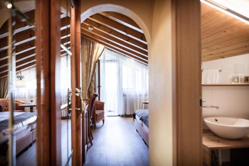 a room with a bathroom with a sink and a bedroom at Relais & Chateaux Schönegg in Zermatt