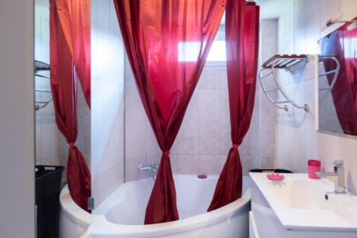uma casa de banho com uma banheira e uma cortina de chuveiro vermelha. em Appartement Fuychaa Proche de Lyon , Eurexpo , stadium , Aréna em Meyzieu