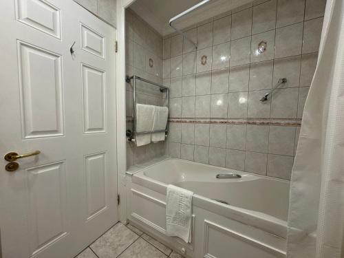 a white bathroom with a tub and a shower at The Killarney Grand in Killarney