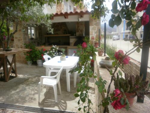 a white table and chairs on a patio with flowers at Argoliki Thalassa in Míloi