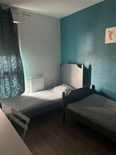 - une chambre avec 2 lits dans une pièce aux murs bleus dans l'établissement Vue sur canal et Stade de france, à Aubervilliers