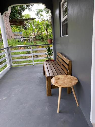 a wooden bench sitting on the side of a porch at Vee's Country Apartments in Micoud