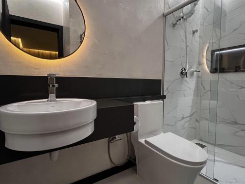 a bathroom with a sink and a toilet and a mirror at Theotokos Flats Apart-hotel in Piauí