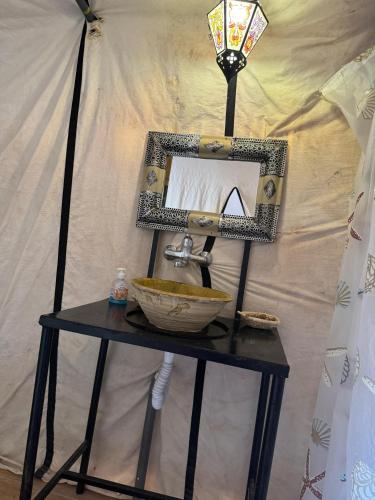 a bathroom sink with a mirror on a table at Sahara Desert Camp in Hassilabied