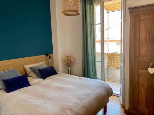 une chambre avec un lit aux murs bleus et une fenêtre dans l'établissement F3 de charme centre ville Ajaccio, à Ajaccio