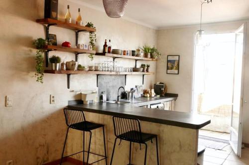 - une cuisine avec un comptoir, 2 chaises et un évier dans l'établissement F3 de charme centre ville Ajaccio, à Ajaccio