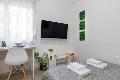 a white room with a bed and a desk and a television at Micro Studio 84 in Xanthi