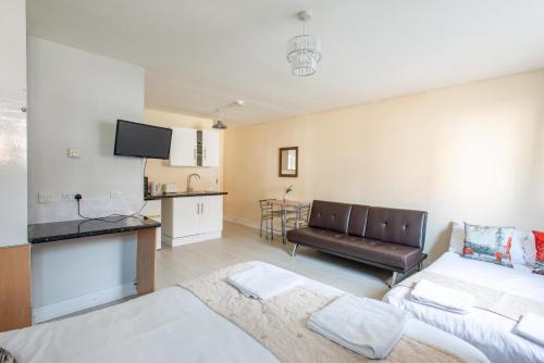 a living room with a couch and a kitchen at Saffron Studios in Orpington
