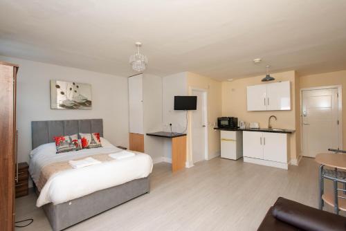 a bedroom with a bed and a small kitchen at Saffron Studios in Orpington