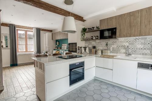une cuisine avec des armoires blanches et un four à plaques de cuisson dans l'établissement Duplex de luxe à Trévoux élégance et confort 100m2 chambres climatisées, à Trévoux