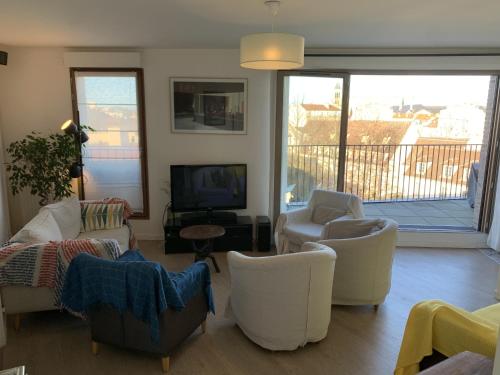 a living room with white chairs and a tv at Whole apartment - Saint-Denis, France in Saint-Denis