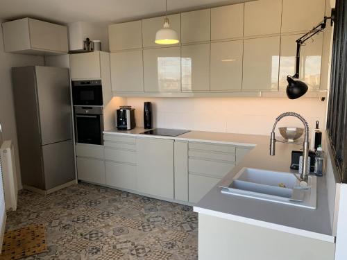 a white kitchen with a sink and a refrigerator at Whole apartment - Saint-Denis, France in Saint-Denis
