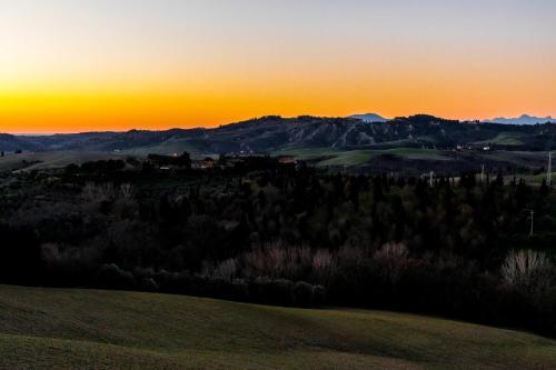 a sunset over a field with a mountain in the background at Borgo Il Poggio Agriturismo in Montaione
