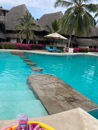 a pool at a resort with palm trees at Harbour key cottages in Malindi