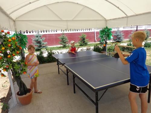 three children standing around a ping pong table in a tent at Aquamarine Inn in Cholpon-Ata