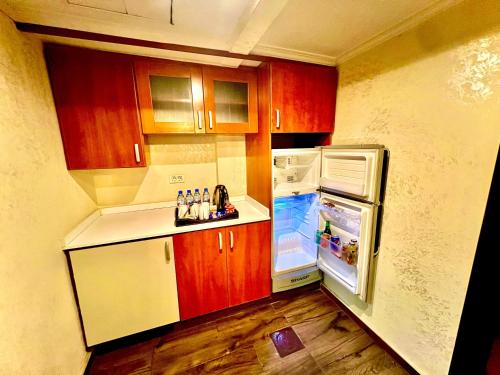 eine kleine Küche mit Holzschränken und einem Kühlschrank in der Unterkunft Queens Suite Hotel in Beirut