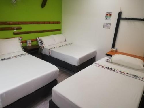 a room with three beds and a green wall at HOTEL PH GIRARDOT in Girardot