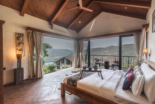 a bedroom with a large bed and large windows at SaffronStays The Totem in Lavasa