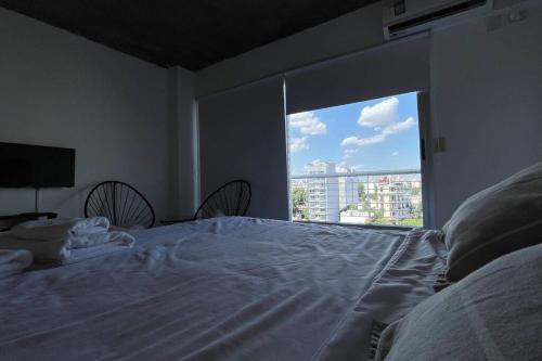 Schlafzimmer mit einem großen weißen Bett und einem großen Fenster in der Unterkunft Studio Palermo Hollywood in Buenos Aires