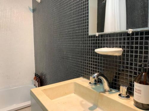 ein Badezimmer mit einem Waschbecken und einer schwarz gefliesten Wand in der Unterkunft Studio Palermo Hollywood in Buenos Aires
