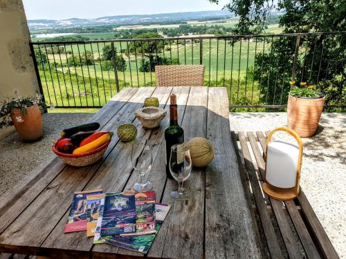 a wooden picnic table with a bottle of wine and fruit at Ferme du Moulin de Paillères - Bain nordique, vue panoramique, piscine - idéal 4-5 personnes in Galapian