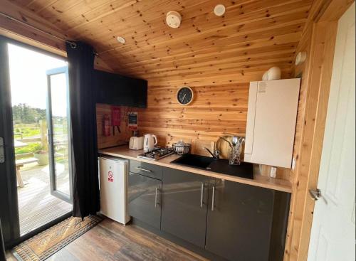 a kitchen with wooden walls and a large window at The Red Kite - 2 person Pet Friendly Glamping Cabin in Dungarvan