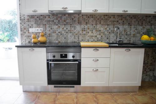 a kitchen with white cabinets and a stove at Alojamento Moinho d`Óbidos in Óbidos