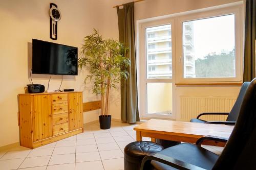 a living room with a tv and a wooden dresser at Chrobry by Baltic Home in Międzyzdroje