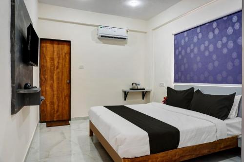 a bedroom with a large bed and a tv at Super OYO Esta Inn in Pune
