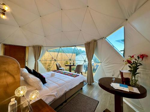 a bedroom with a tent with a bed and a table at MISKI SAMAY DOMO BOUTIQUE in Urubamba