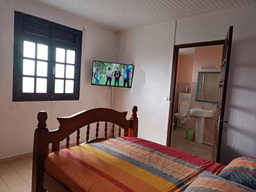 een slaapkamer met een bed en een tv aan de muur bij Maison de 4 chambres avec jacuzzi terrasse et wifi a Riviere Pilote a 3 km de la plage in Rivière-Pilote