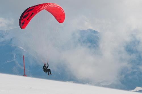 a person riding a parachute on a snow covered slope at Mathiasl Panorama Ferienwohnungen in Bodensdorf