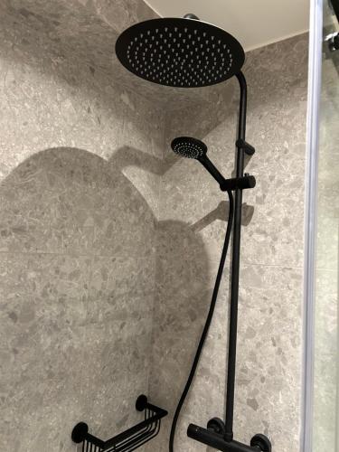 a shower with a black shower head in a shower at Louis-Gabriël in De Panne