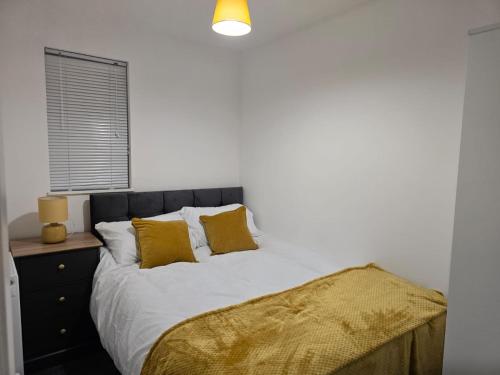 ein Schlafzimmer mit einem Bett mit zwei gelben Kissen in der Unterkunft Stylish 3 bedrooms in Bradwell