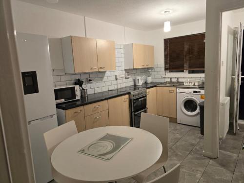 eine Küche mit einem weißen Tisch, einem Tisch und Stühlen in der Unterkunft Stylish 3 bedrooms in Bradwell