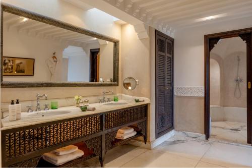 a bathroom with a sink and a large mirror at La Villa des Orangers - Relais & Châteaux in Marrakesh