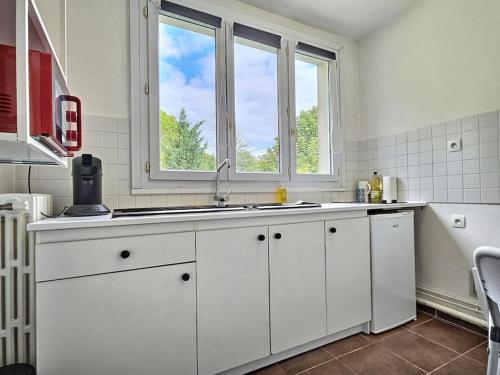 een witte keuken met een wastafel en een raam bij L'Escapade Perchée*Disney*Paris* in Pomponne