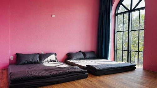a room with two beds in front of a pink wall at Thong Dong Homestay in Phước Lý