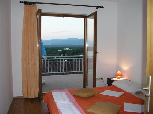 a bedroom with a bed and a balcony with a view at Apartmani Bura in Njivice