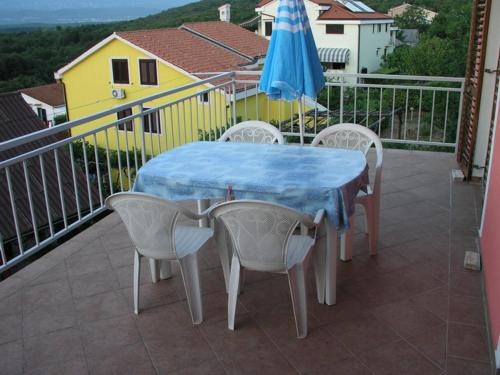 una mesa y sillas en un balcón con sombrilla en Apartmani Bura en Njivice