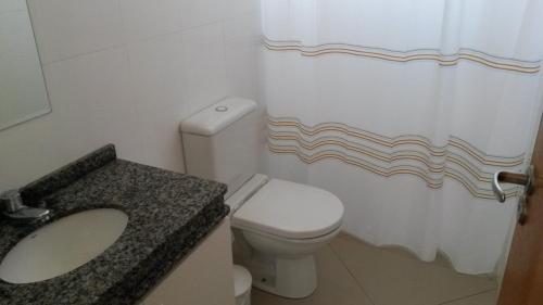 a bathroom with a toilet and a sink and a shower curtain at Apartamento Central Curitiba in Curitiba