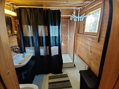 a bathroom with a black shower curtain and a sink at Kivakko Saariselän paratiisi - Oma ranta & sauna in Saariselka